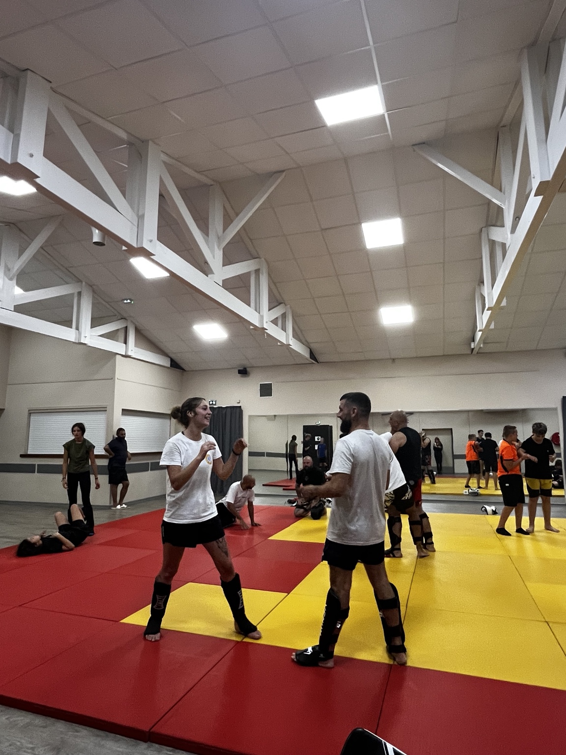 Deux pratiquants travaillent debout sur les tatamis rouges et jaunes du club NAK SU à Bras
